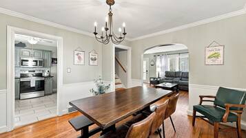 Un comedor con una mesa y sillas de madera, una cocina al fondo y una escalera que lleva a otra habitación.