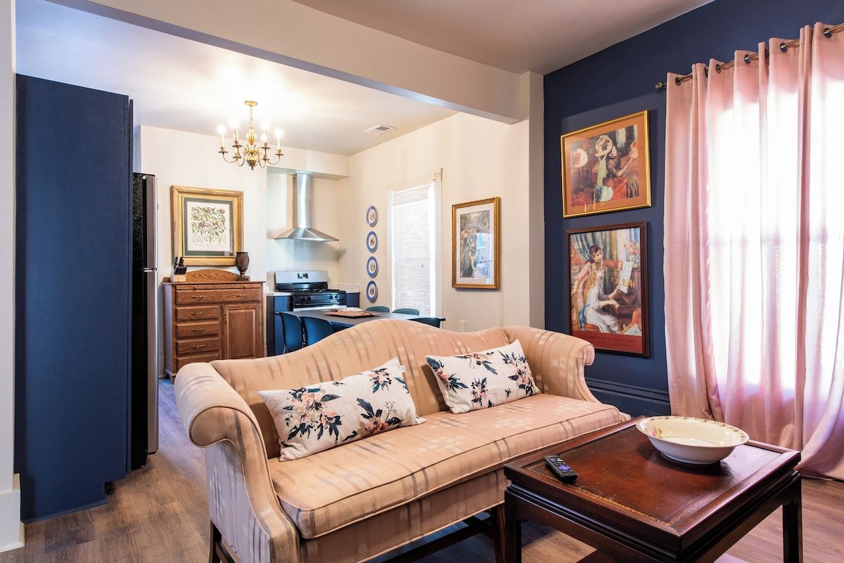 A living room with a sofa, coffee table, and artwork on the walls.