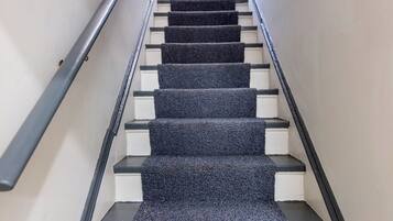 A staircase with a carpeted landing and a handrail on the left.