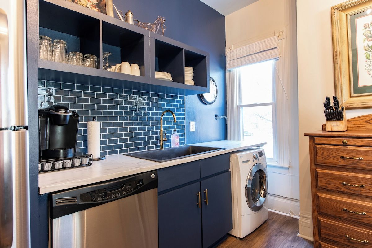 A kitchen with a dishwasher, washing machine, and a sink with a faucet.