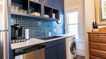 A kitchen with a dishwasher, washing machine, and a sink with a faucet.