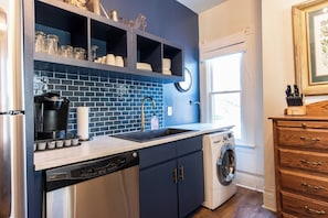 A kitchen with a dishwasher, washing machine, and a sink with a faucet.