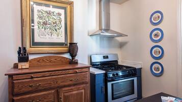 A kitchen with a stove, oven, and a framed botanical illustration on the wall.