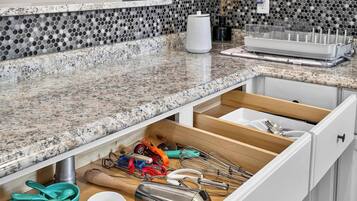 A kitchen with a granite countertop, a drawer organizer, and various kitchen utensils.