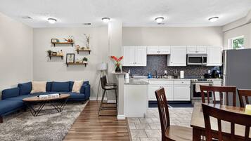 A modern kitchen with white cabinets, a microwave, and a stove.