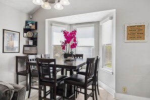 A dining area with a table and chairs, a potted plant, and a motivational quote on the wall.
