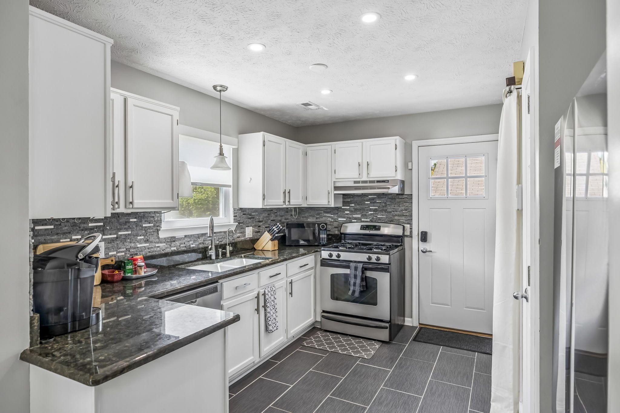 A modern kitchen with white cabinets, a stainless steel oven, and a granite countertop.