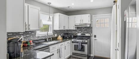 A modern kitchen with white cabinets, a stainless steel oven, and a granite countertop.