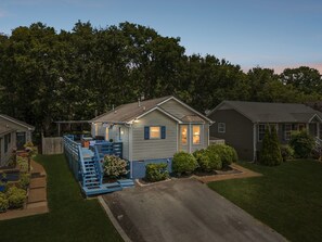 Ein Bungalow mit Veranda, kleiner Terrasse und gepflegtem Rasen.