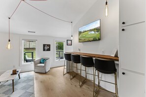 Eine moderne Küche mit Barbereich, großen Fenstern und Blick auf einen Golfplatz.
