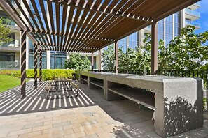 An outdoor seating area with a pergola, benches, and a concrete planter. - Premium 1BR - Creek Harbour - Pool, Sea View (Dubai)