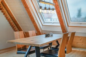 A dining area with a wooden table and chairs, a skylight, and a view of the outdoors.
