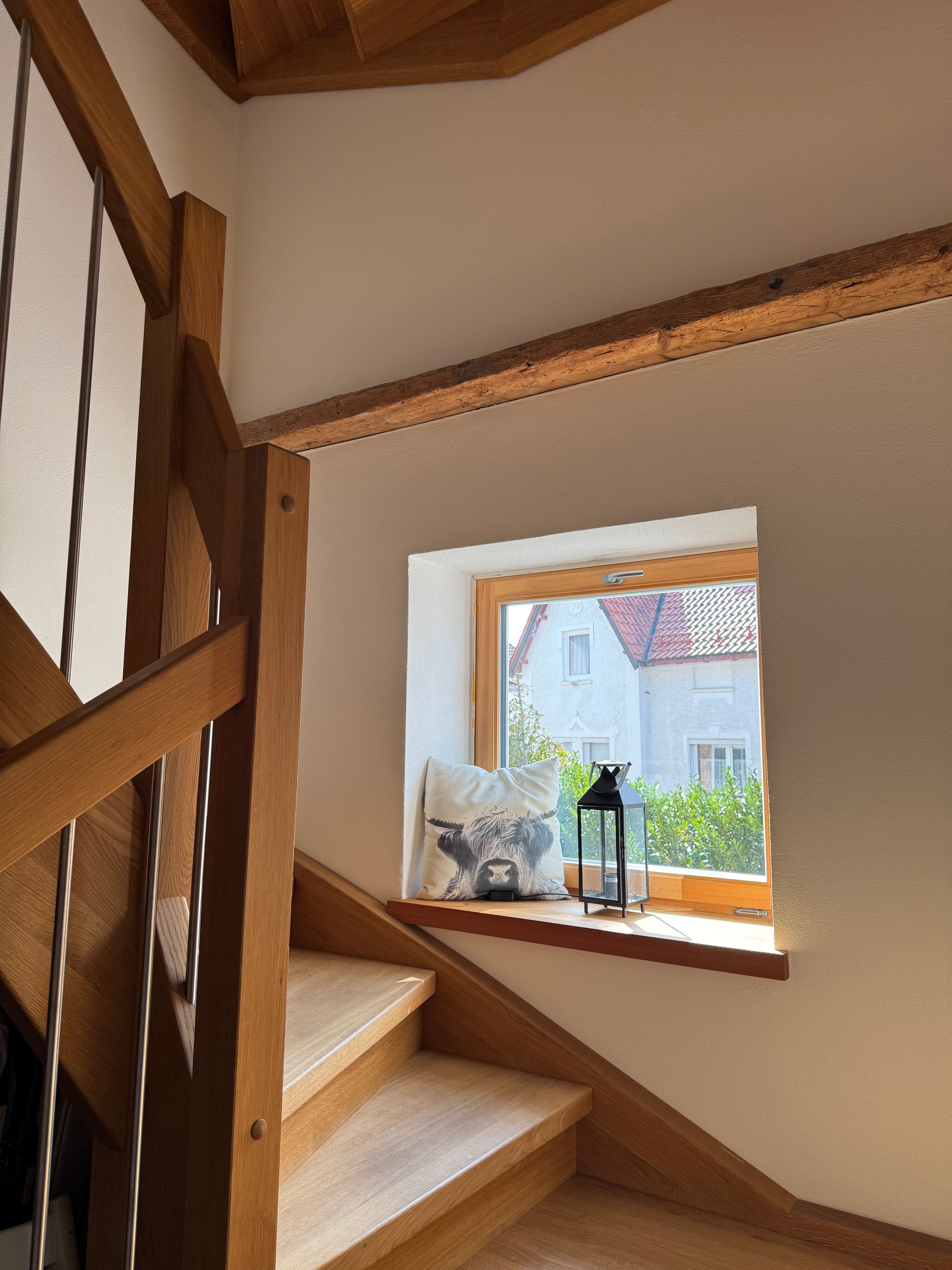 En trätrappa med ett inbyggt fönster som vetter ut mot ett bostadsområde.