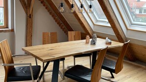 A dining area with a wooden table and chairs, a skylight, and a staircase. - DG Apartment alpenchic with Balcony in Ottobeuren – Sleeps 2 (Ottobeuren)