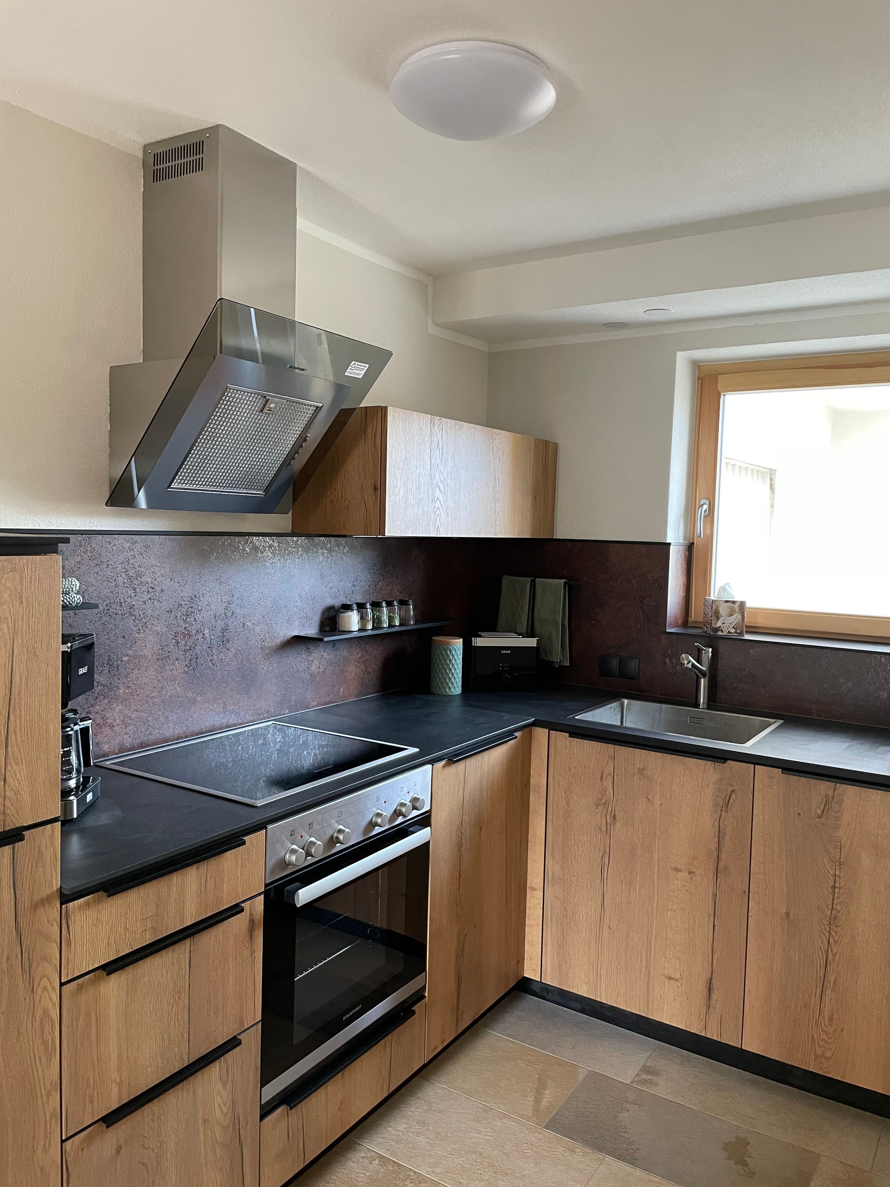Eine moderne Küche mit eingebautem Herd, Backofen und einem Fenster über der Spüle.