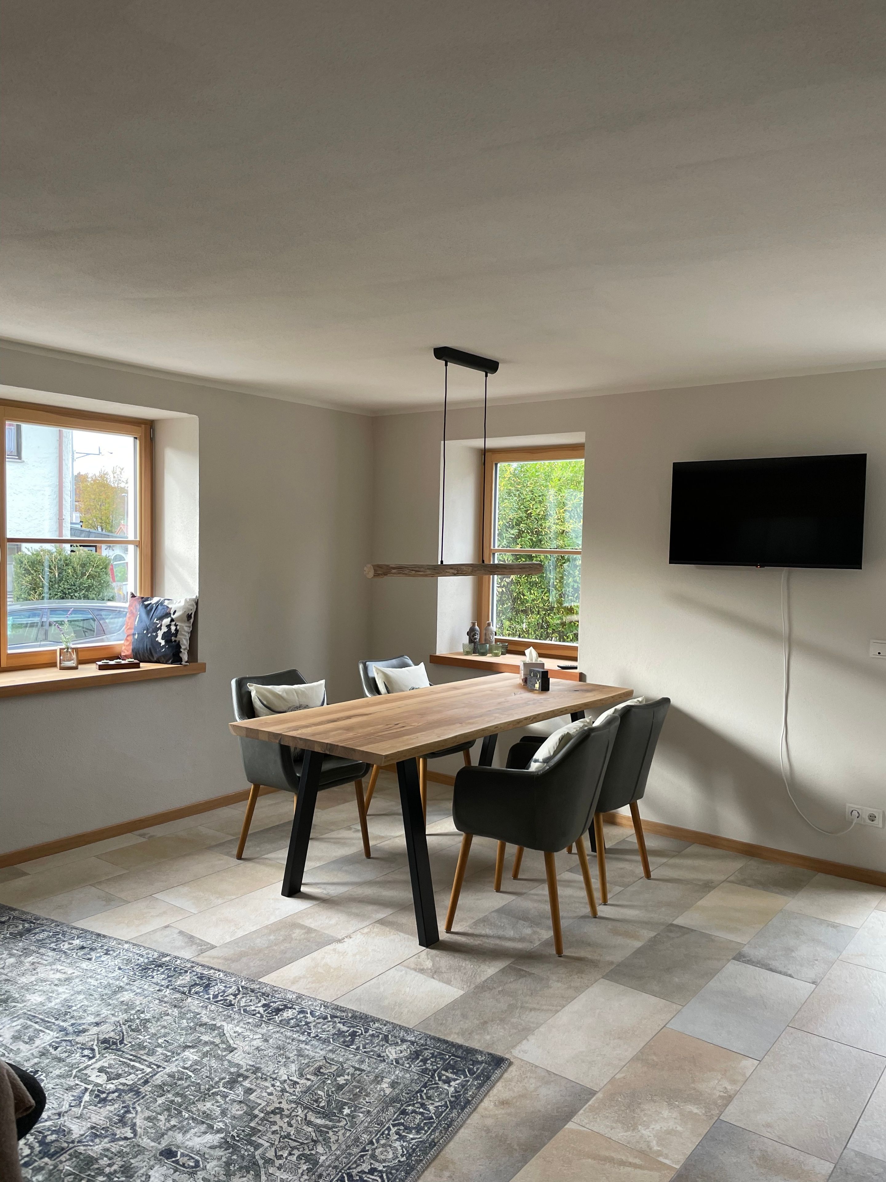 Ett modernt matrum med ett träbord, svarta stolar och en mönstrad matta.