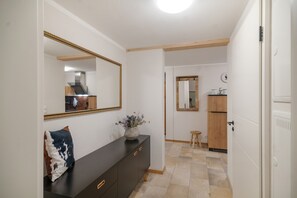 A hallway with a dark wooden dresser, a mirror, and a vase with flowers.