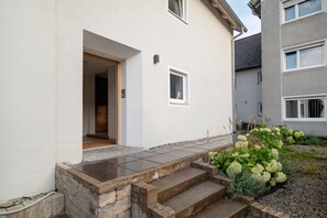 A residential building with a white exterior, a wooden door, and a small window.