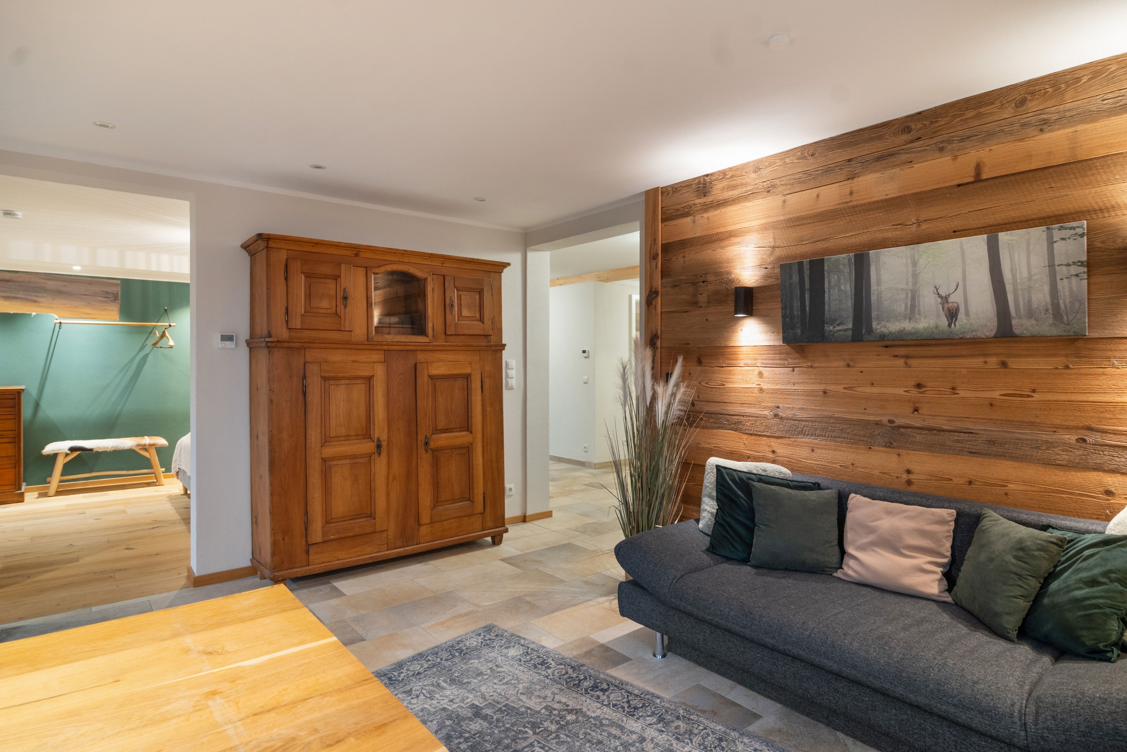 Una sala moderna con paneles de madera, un sofá gris con cojines, un aparador de madera y un cuadro grande.