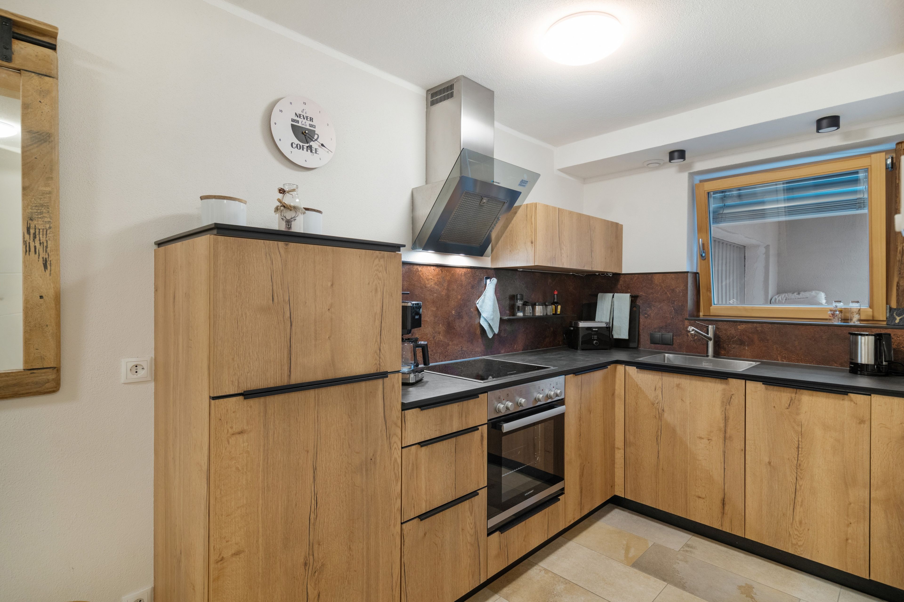 Eine moderne Küche mit Holzschränken, einer Edelstahlspüle und einem eingebauten Backofen.