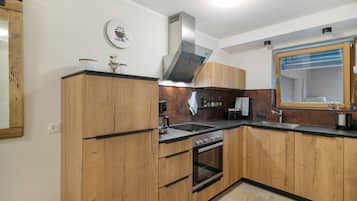 Eine moderne Küche mit Holzschränken, einer Edelstahlspüle und einem eingebauten Backofen.