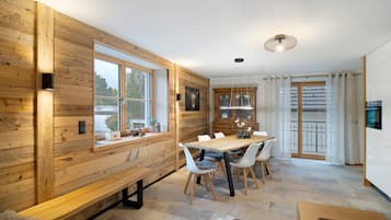 A modern kitchen with wooden walls, a dining table with chairs, and a bench.
