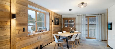 A modern kitchen with wooden walls, a dining table with chairs, and a bench.