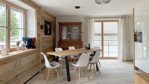 Una cocina moderna con una mesa de comedor de madera, sillas blancas y un horno empotrado.