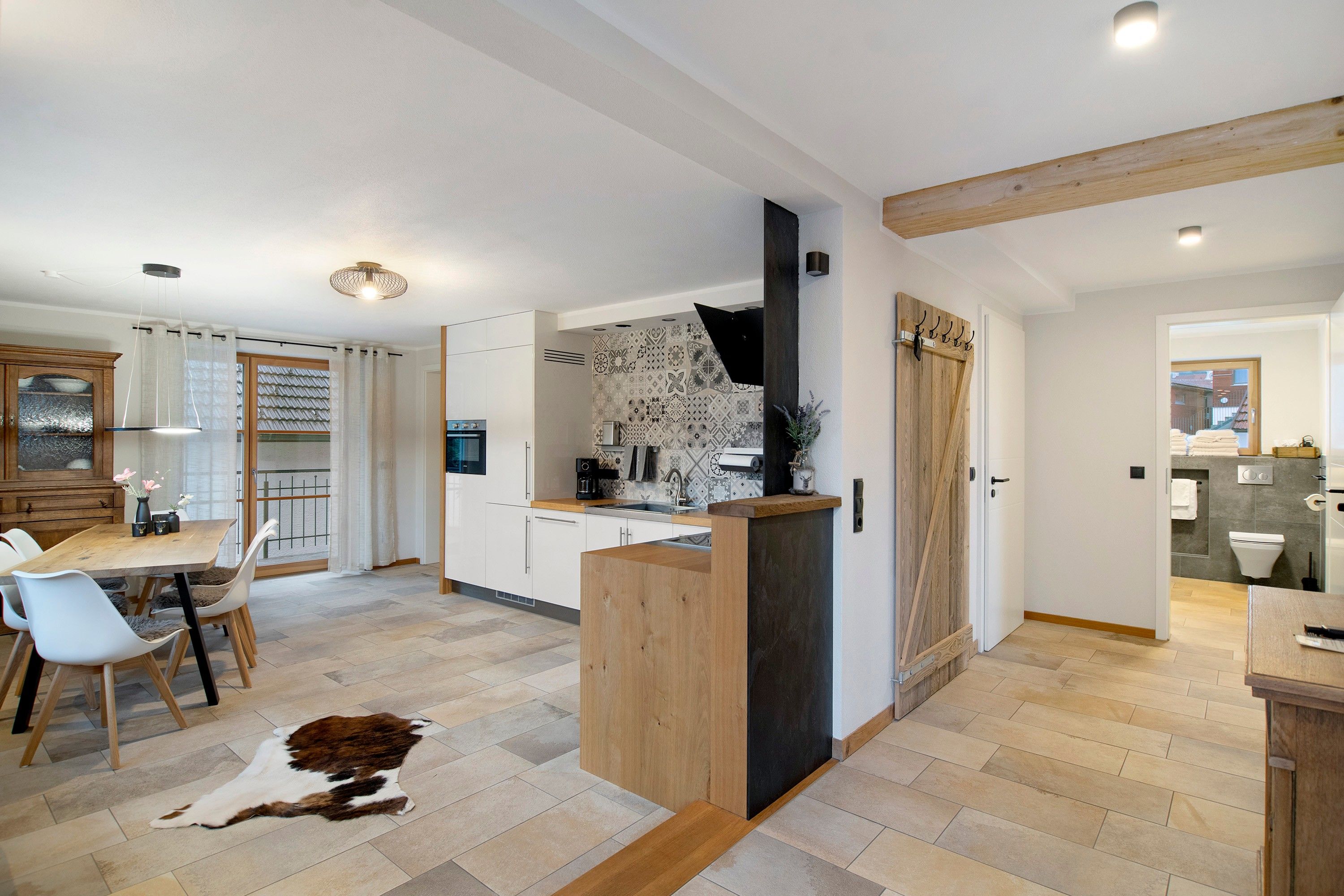 Eine moderne Küche mit weißen Schränken, einer Holz Arbeitsplatte und einer schwarzen Dunstabzugshaube.