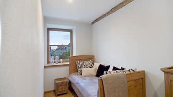 A bedroom with a wooden bed, a nightstand, a window with a view of buildings, and a ceiling light.
