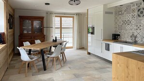 Una cocina moderna con una mesa de comedor de madera, sillas blancas y un horno empotrado.