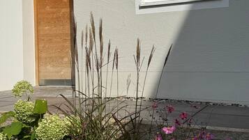 Ein modernes Gebäude mit einer Holztür, einem Fenster und einem Garten mit verschiedenen Pflanzen und Blumen.