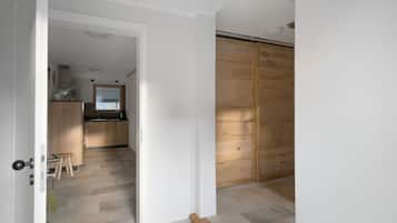 A room with a wooden floor, a kitchen area with wooden cabinets, and a sliding door.