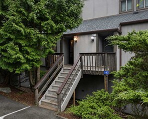 A building with a staircase leading to a porch, surrounded by trees. - Camelback Mountain Escape Sleeps 12 (Tannersville)