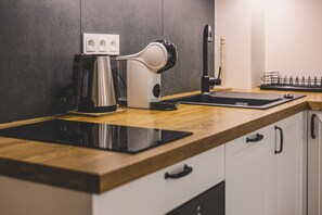 A modern kitchen with a built-in induction cooktop, a coffee maker, and a kettle.