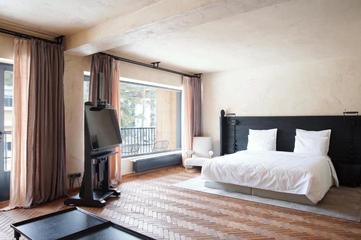 Une chambre d’hôtel équipée d’un lit, d’une télévision, d’une chaise et offrant une vue sur l’extérieur.