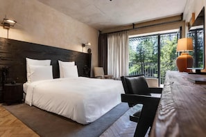 Une chambre d’hôtel avec un grand lit, un bureau, une chaise et une fenêtre avec des rideaux.