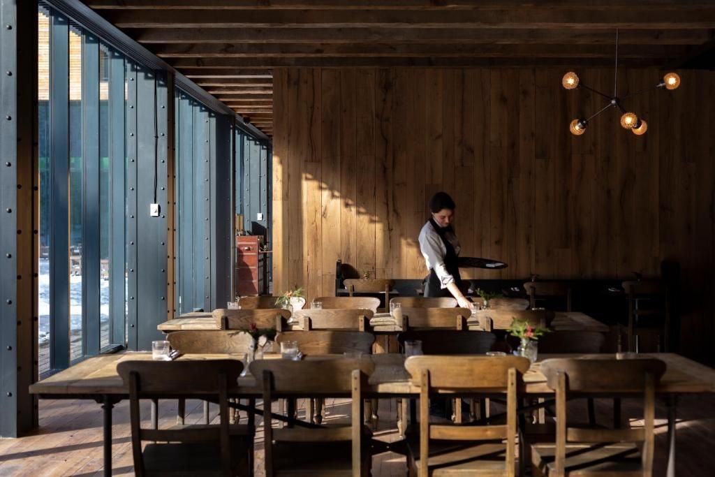 Een restaurant met houten meubels en een bedienend personeelslid.