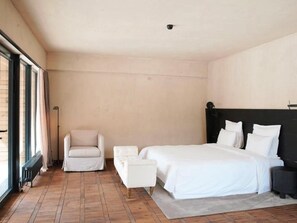 Un dormitorio con una cama grande, una silla y una mesita de noche.