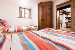 Ein Zimmer mit einem Bett, einem Fenster, einem Holzschrank und einem Spiegel, der einen Essbereich zeigt.