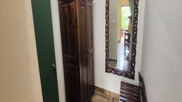 Un pasillo con un armario de madera, un espejo con marco decorativo y un banco.