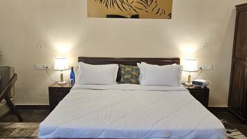A hotel room with a large bed, two bedside lamps, a wall-mounted tiger artwork, and a patterned bench.