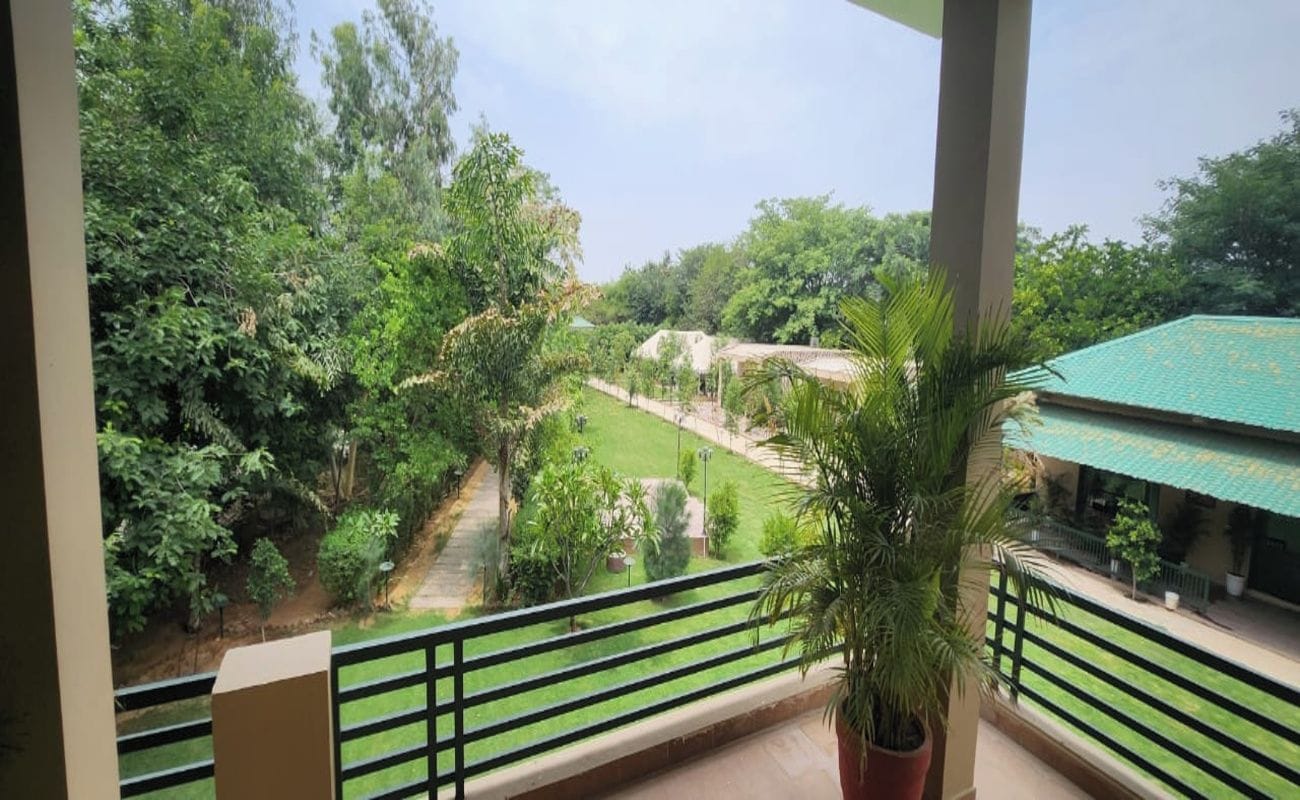 Un balcón con vistas a un paisaje verde, un sendero y un edificio con techo verde.