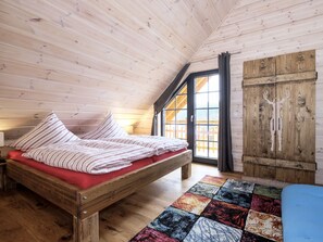 A wooden room with a bed, a colorful rug, and a wooden wardrobe. - Holiday Home in Schierke With Sauna (Wernigerode)