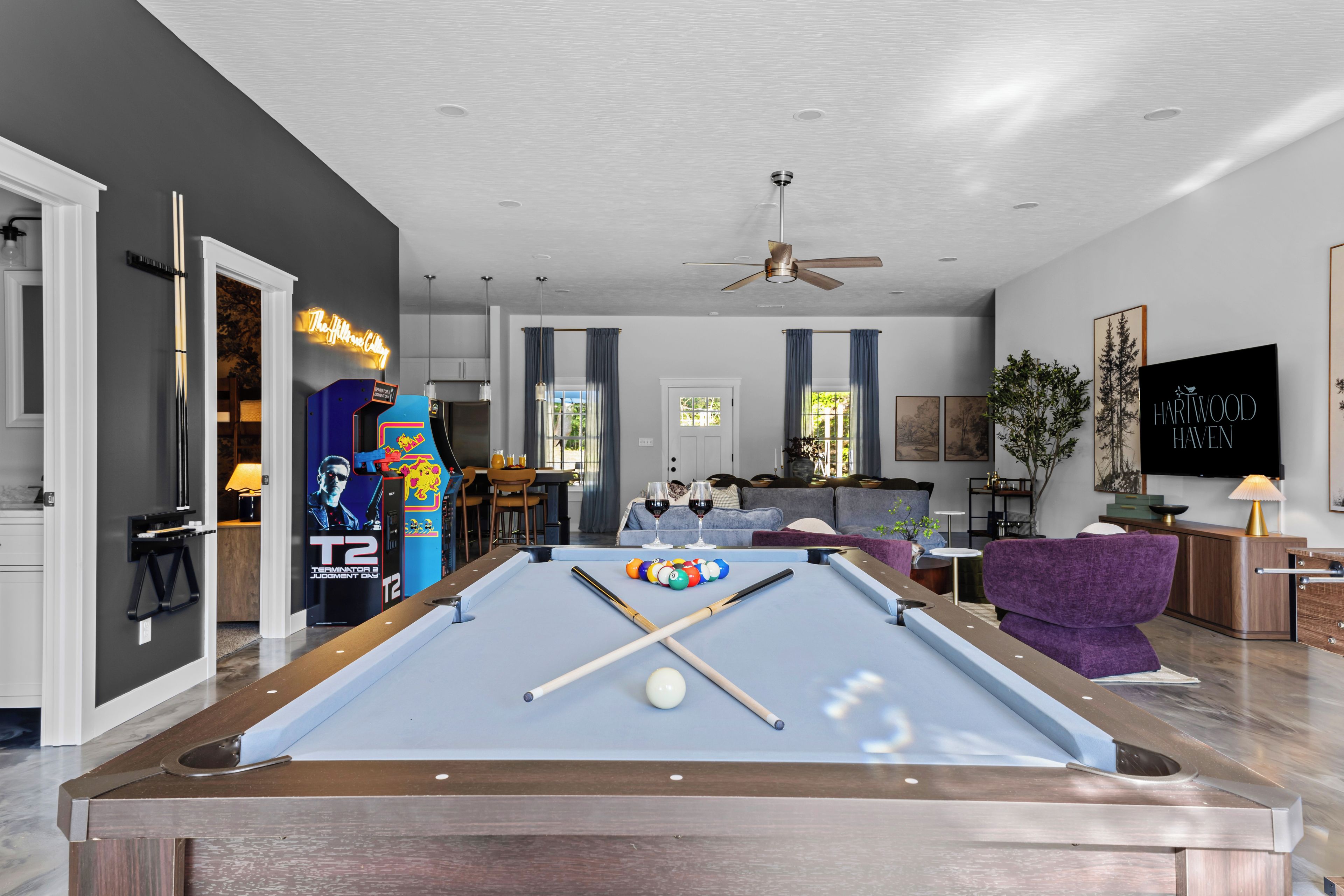 Un salon moderne avec une table de billard, un néon et un téléviseur.