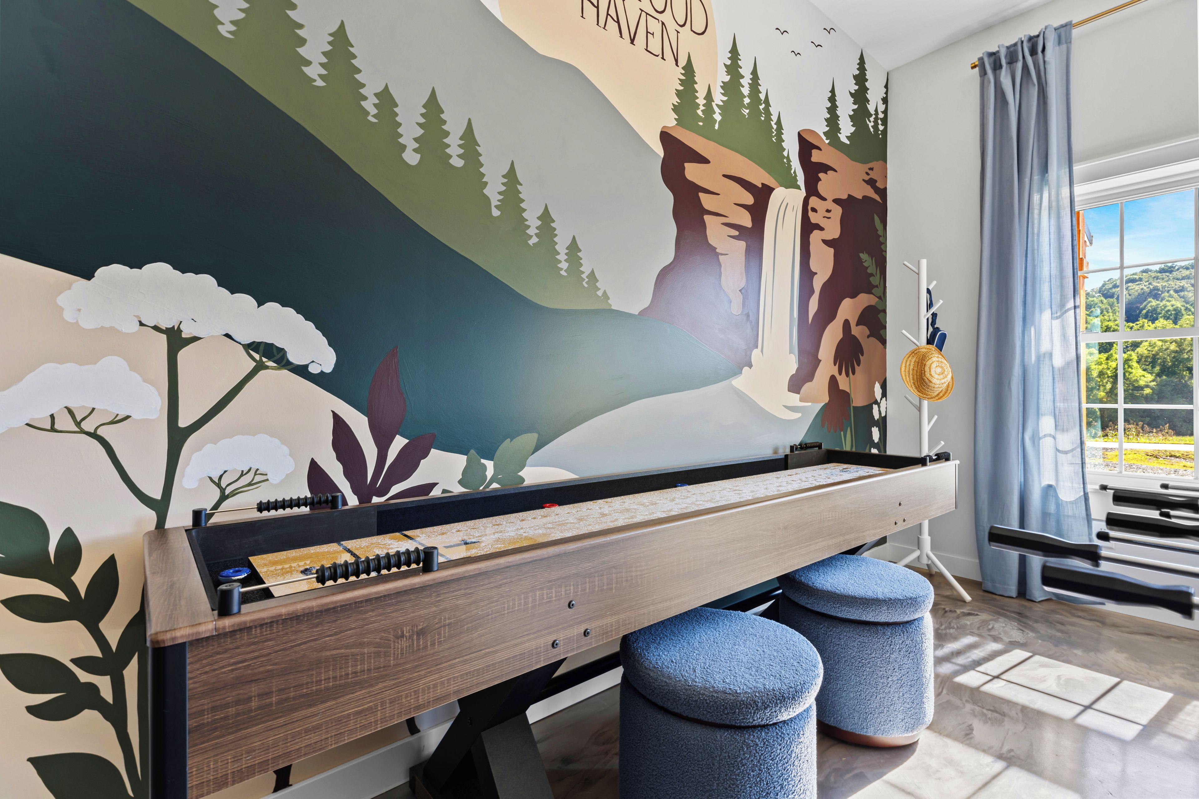 Une pièce avec un piano, des poufs, une fresque murale et une fenêtre donnant sur un beau paysage.