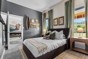 A bedroom with a bed, a nightstand, a window with curtains, and wall art. - Woodland Retreat - Near Ash Cave - Hot Tub, Sauna, Game Room (Laurelville)