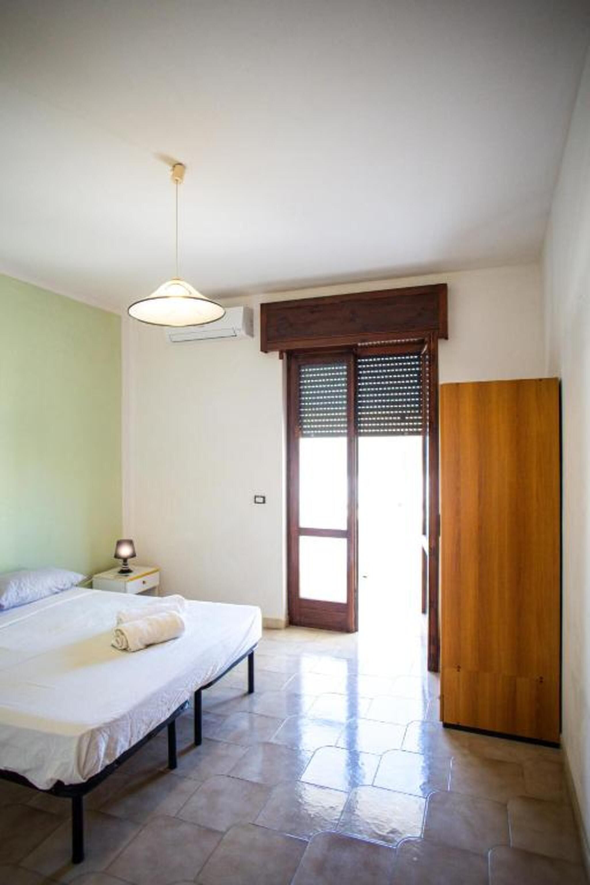 Un dormitorio con cama, lámpara de noche y armario de madera.