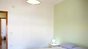 Un dormitorio con cama, mesita de noche, lámpara y una lámpara colgante.