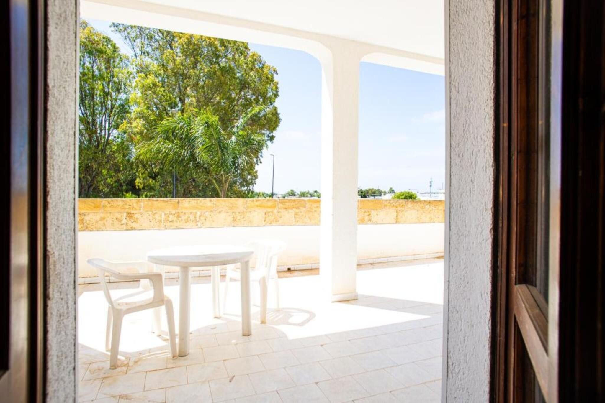 Eine Terrasse im Freien mit Tisch und Stühlen, eine Steinmauer und ein Baum im Hintergrund.